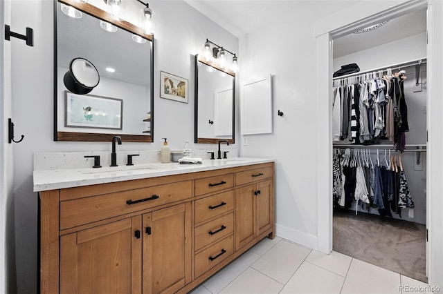 8276 E 28th Dr, Denver, CO 80238 - bathroom with double vanity, tile patterned floors, a walk in closet, and baseboards