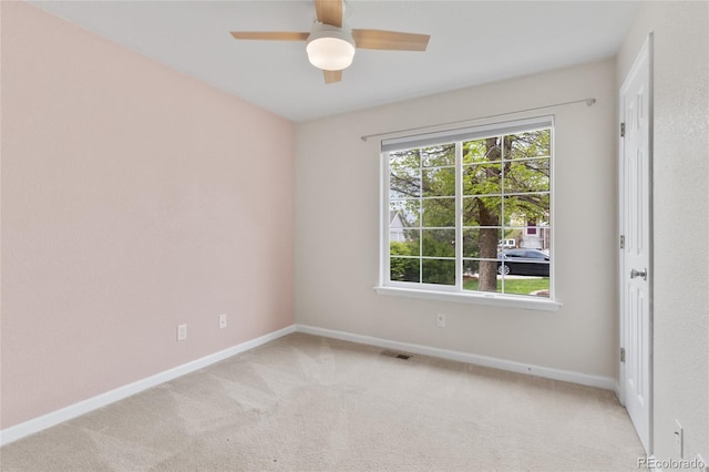 unfurnished room with baseboards, a ceiling fan, and light carpet