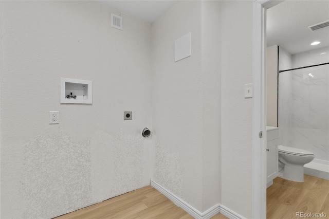 clothes washing area with hookup for an electric dryer, light wood finished floors, washer hookup, and baseboards