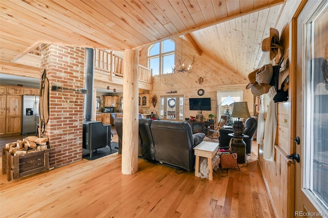 living room featuring light wood-type flooring, wood ceiling, high vaulted ceiling, a wood stove, and wood walls