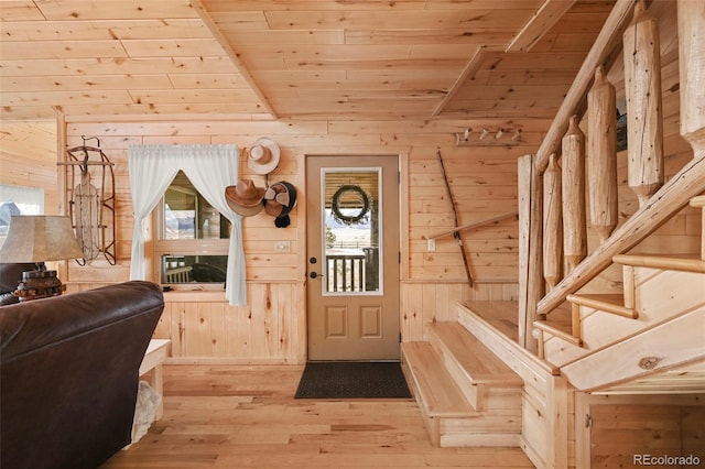 foyer featuring light hardwood / wood-style floors, wood walls, wood ceiling, and vaulted ceiling