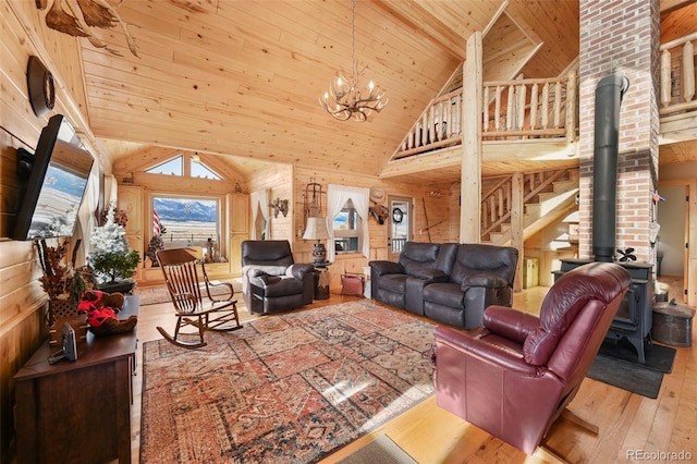 living room with light wood-type flooring, high vaulted ceiling, wooden ceiling, a notable chandelier, and a wood stove