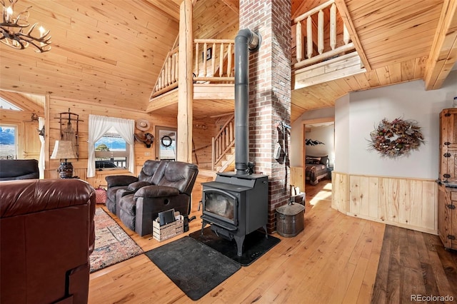 living room with high vaulted ceiling, light hardwood / wood-style floors, a wood stove, and wooden walls