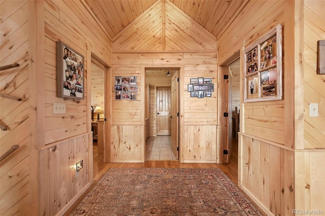 hall with wood walls and vaulted ceiling