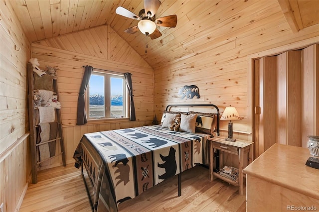 bedroom featuring light hardwood / wood-style floors, ceiling fan, and wooden walls