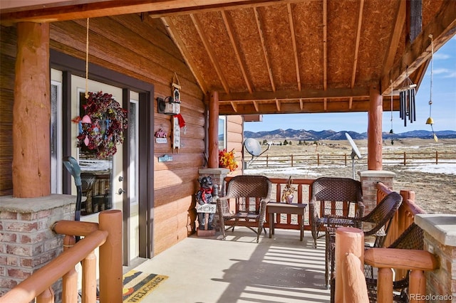 snow covered patio with a mountain view and a porch