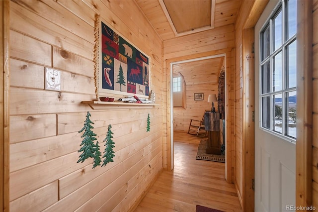 hall featuring light hardwood / wood-style floors, wooden walls, and wood ceiling