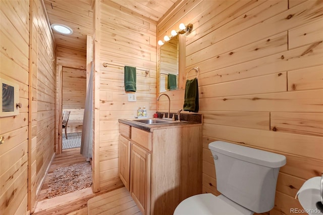 bathroom with vanity, toilet, and wood walls