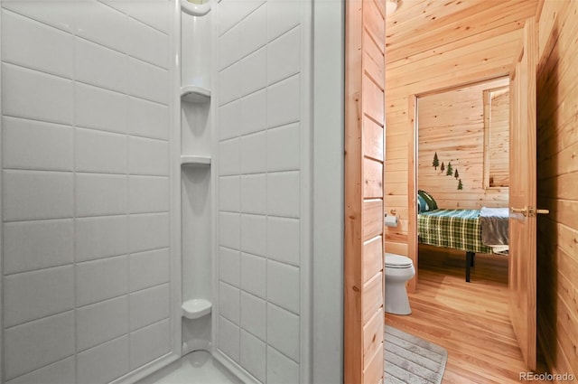 bathroom featuring hardwood / wood-style floors, wood walls, and toilet