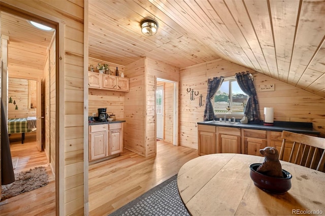 kitchen featuring wood ceiling, vaulted ceiling, wooden walls, light brown cabinets, and light hardwood / wood-style flooring