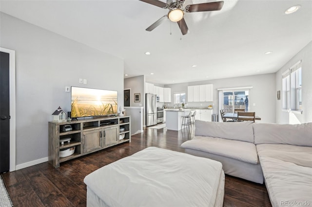 living room with dark hardwood / wood-style flooring and ceiling fan