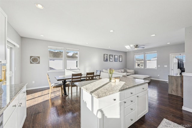 kitchen with a kitchen island, light stone counters, and white cabinetry