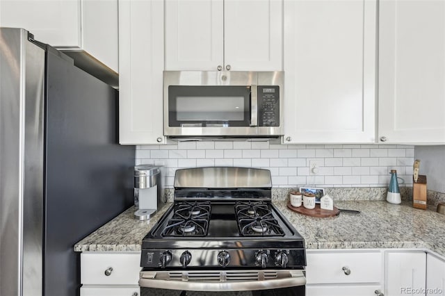 kitchen with white cabinets, stainless steel appliances, light stone counters, and tasteful backsplash