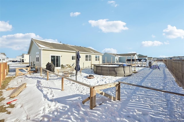 snow covered property with a fenced in pool and an outdoor fire pit