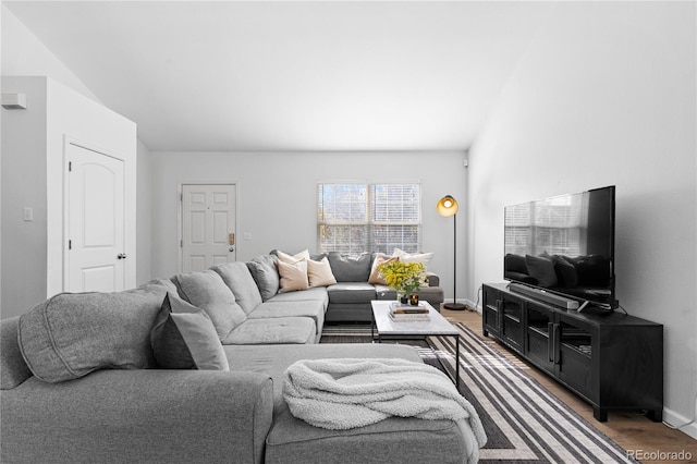 living room featuring wood finished floors, lofted ceiling, and baseboards