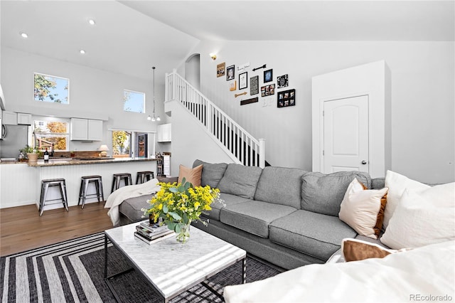 living area featuring dark wood finished floors, high vaulted ceiling, stairway, and recessed lighting