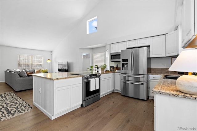 kitchen with appliances with stainless steel finishes, a peninsula, dark wood-style floors, high vaulted ceiling, and open floor plan