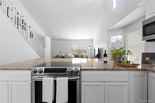 kitchen with stainless steel appliances, open floor plan, stone countertops, and white cabinets