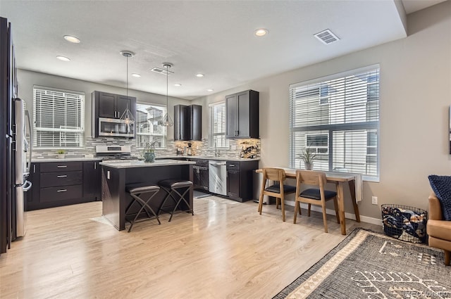 3795 Depew St Unit D, Wheat Ridge, CO 80212 - kitchen with appliances with stainless steel finishes, light wood-style floors, a kitchen island, decorative backsplash, and recessed lighting