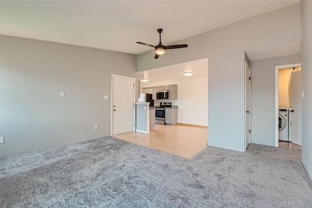 unfurnished living room with ceiling fan, washer / clothes dryer, and light colored carpet