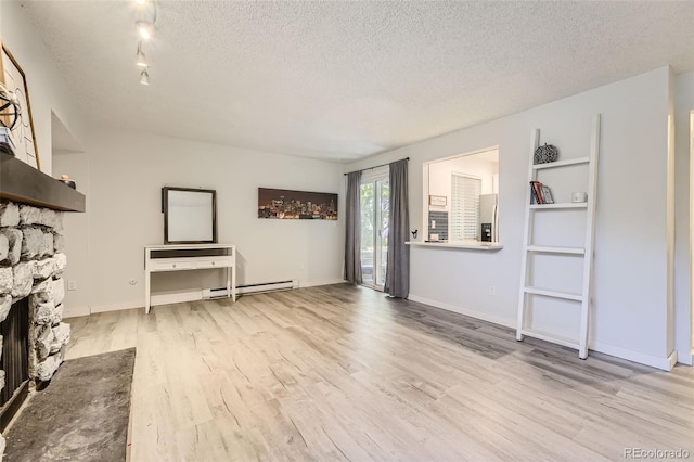 unfurnished living room with a baseboard heating unit, a stone fireplace, a textured ceiling, and wood finished floors