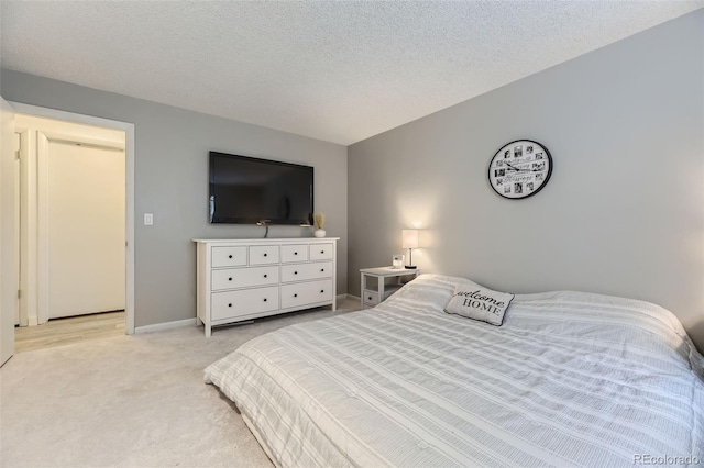 bedroom featuring light carpet, baseboards, and a textured ceiling