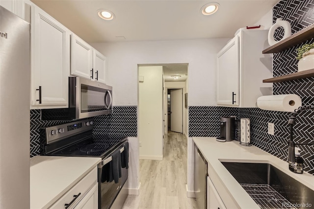 kitchen with stainless steel appliances, light countertops, white cabinetry, open shelves, and recessed lighting