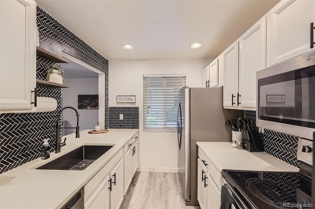 kitchen featuring white cabinets, appliances with stainless steel finishes, a sink, open shelves, and backsplash