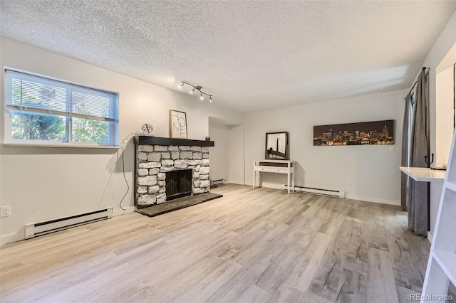 living room featuring a textured ceiling, a baseboard heating unit, wood finished floors, and a stone fireplace