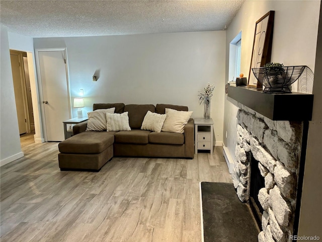 living area featuring light wood-style floors, a baseboard radiator, baseboards, and a textured ceiling