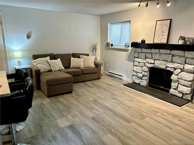 living area featuring a baseboard heating unit, a textured ceiling, a fireplace, and wood finished floors