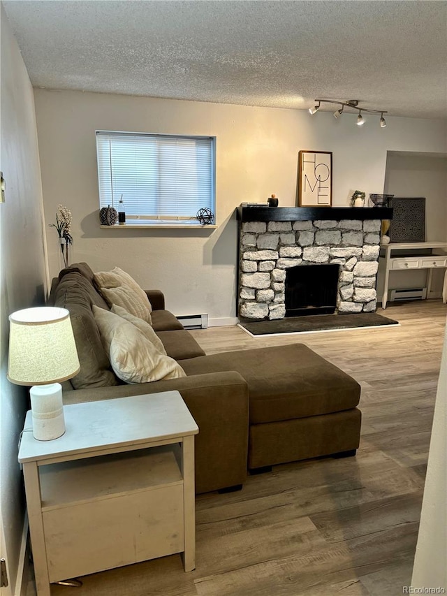 living room featuring a textured ceiling, baseboard heating, a fireplace, and wood finished floors