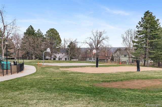 view of property's community with a yard, community basketball court, and fence