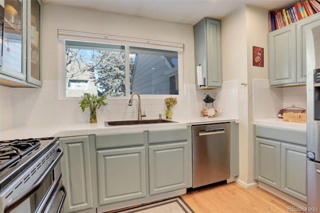 kitchen featuring dishwasher, light countertops, light wood finished floors, and a sink