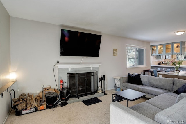 living area with baseboards, a fireplace with flush hearth, and carpet flooring