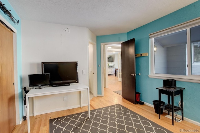 office space with baseboards, a textured ceiling, and wood finished floors