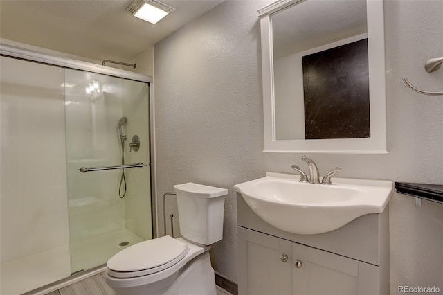 full bathroom with a shower stall, toilet, vanity, and a textured wall