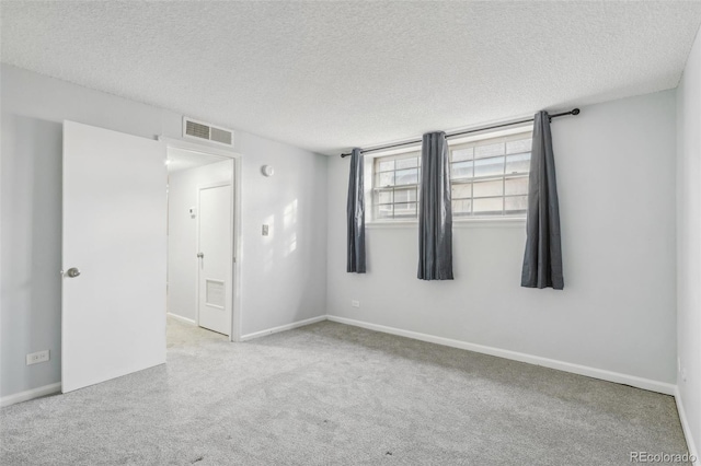 carpeted empty room with a textured ceiling