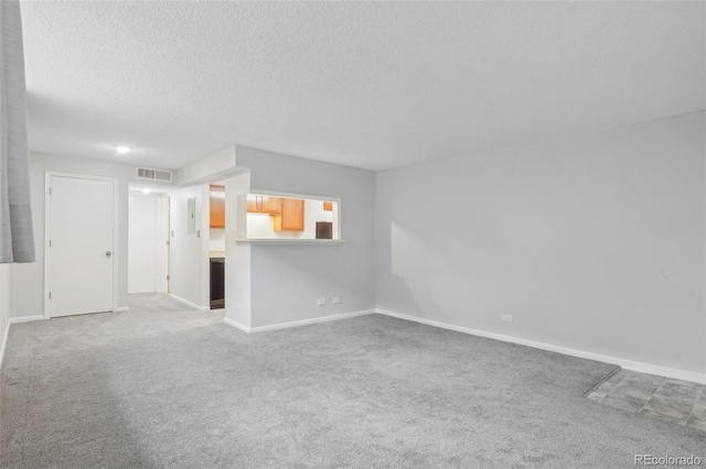 unfurnished living room featuring a textured ceiling and light carpet