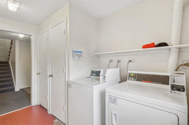 laundry room featuring washing machine and clothes dryer and a textured ceiling