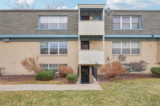 view of front of home featuring a balcony and a front lawn