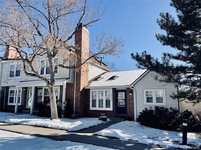 view of front facade featuring brick siding and a chimney