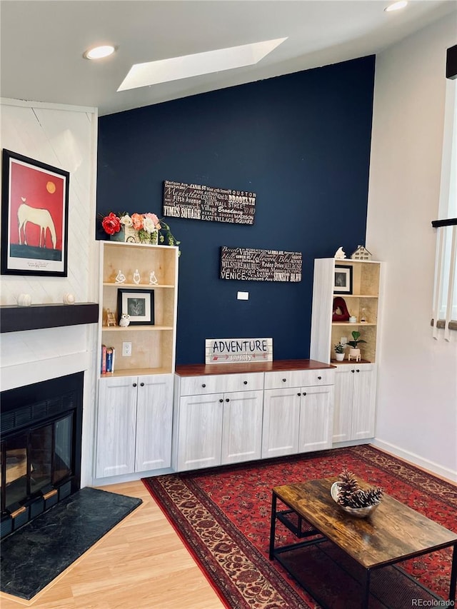 playroom featuring light wood finished floors, a fireplace with flush hearth, and recessed lighting