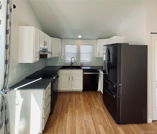 kitchen with light wood-style flooring, under cabinet range hood, a sink, black appliances, and dark countertops