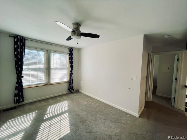 carpeted empty room featuring ceiling fan and baseboards