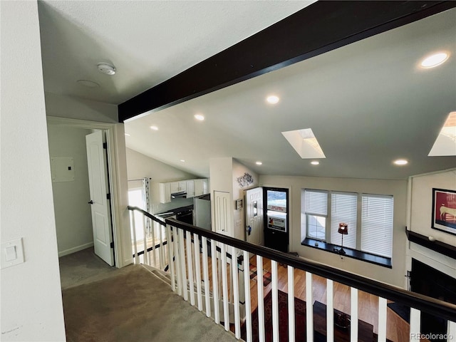 hallway featuring lofted ceiling with skylight, recessed lighting, carpet floors, and an upstairs landing