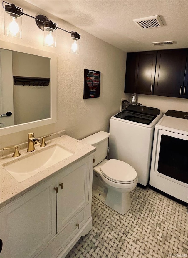 bathroom with toilet, a textured ceiling, visible vents, and washer and dryer