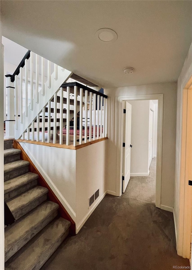 stairway with baseboards, visible vents, and carpet flooring