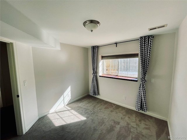 spare room featuring carpet floors, visible vents, and baseboards