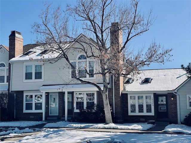 view of front facade with a chimney and brick siding